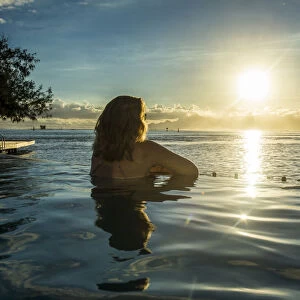 Woman enjoying the sunset in a swimming pool with Moorea in the background, Papeete