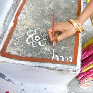 Woman painting her doorstep with rice flour paste, making rangoli design Diwali Festival decorations, Udaipur