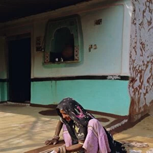 Woman painting the wall of a village house