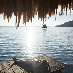 Woman relaxing on dock, El Remate, Lago Peten Itza, Guatemala, Central America