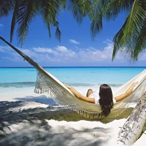 Woman sitting in hammock on beach, Maldives, Indian Ocean, Asia