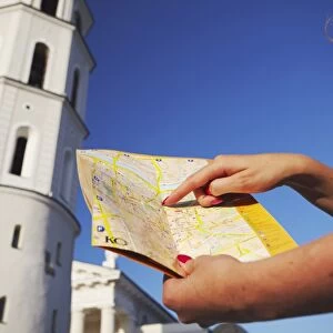 Woman standing outside Vilnius Cathedral Belfry with map, Vilnius, Lithuania