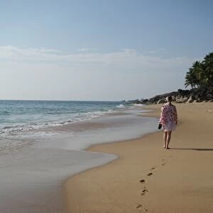 Woman walking leaving footprints on deserted beach, Niraamaya, Kovalam, Kerala, India