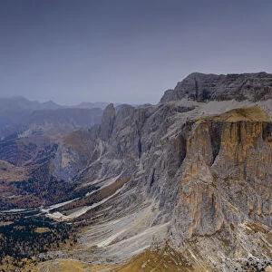 Woods in autumn at foot of Sass Pordoi and Sella mountain at dawn, aerial view