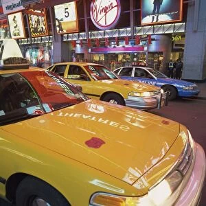 Yellow cabs on the street at night in Times Square, with Virgin Megastore in the background