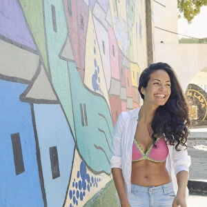 Young Brazilian woman happy and smiling next to a graffiti wall in Lapa, central Rio de Janeiro