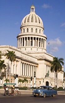 Cuban Prints: A 1950s car and rickshaw pass the Capitolio in central Havana, Cuba, West Indies