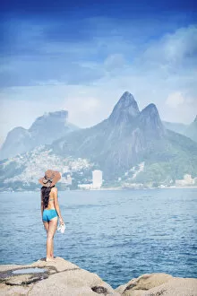 Holiday Makers Gallery: A 20-25 year old young Brazilian woman standing on the Arpoador rocks with Ipanema