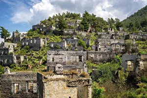 Overgrown Prints: Abandoned houses in Kayakoy ghost town nestled in mountains and lush vegetation in Fethiye Turkey