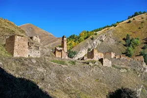Terrain Prints: Abandoned mountain village shows remnants of old structures set against a clear blue sky in Chechnya