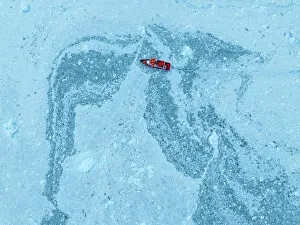 Open Water Prints: Aerial of a little ship floating between the ice below the Eqi glacier