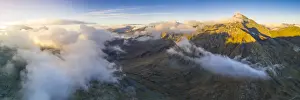Aerial panoramic of sea of clouds over Pizzo Tambo and bends of the Spluga Pass road