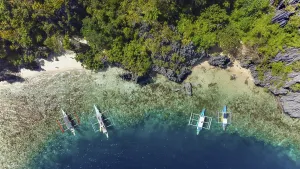 Aerials Prints: An aerial shot captures traditional Filipino boats floating on the clear waters close to a secluded beach