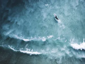 aerial shot capturing surfer navigating clear blue waves portugal