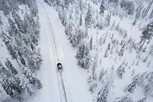 Finland Prints: Aerial shot of a car crossing the boreal forest covered with snow