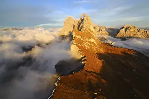 Aerial shot from Seceda of Odle surrounded by clouds at sunset in the Dolomites, Val Funes