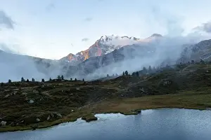 Mountain Pass Prints: Aerial view of Fletschhorn and Galehorn mountains in fog at dawn from Hopschusee lake