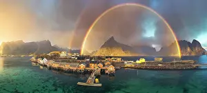 Sakrisoy Prints: Aerial view of idyllic rainbows over Olstind mountain and fishermen cabins by the sea