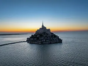 Maritime Prints: Aerial view of Mont St Michel with surrounding water at sunset in France