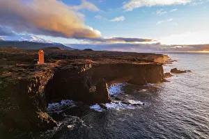 Vesturland Prints: Aerial view of the orange Svortuloft lighthouse on top of the basalt cliffs at sunset