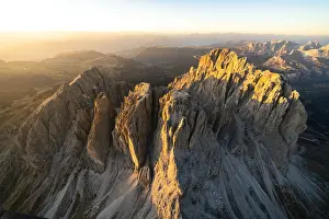 Fassa Valley Prints: Aerial view of Sassolungo and Sassopiatto lit by the warm autumn sunset, Val Gardena