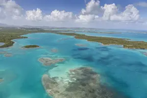 Aerial view of sections of reef scattered along the rugged coastline and rich tropical