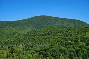 Trail Prints: Aerial view shows dense forests and mountains of Una National Park in Bosnia and Herzegovina with clear blue sky