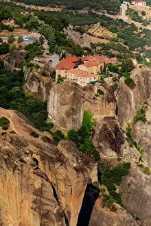 Monasteries Prints: Aerial view shows Meteora monastery on steep rock in green landscape with distant buildings in Thessaly Greece