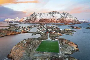 Snowcapped Prints: Aerial view of soccer stadium and Henningsvaer village during winter dawn