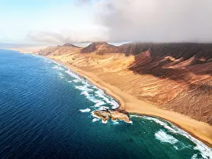 Azure Prints: Aerial view of the wild Cofete beach in between volcanic mountains and sea