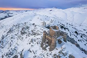 Aerial winter view of Rocca Calascio castle and the Santa Maria della Pieta church in the snowy landscape at dusk, Campo Imperatore, L'Aquila province, Abruzzo region, Italy, Europe