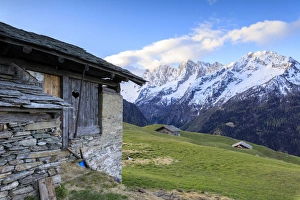 Soglio Prints: Alpine hut framed by meadows and snowy peaks at dawn, Tombal, Soglio, Bregaglia Valley