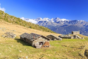 Alpine huts framed by snowy peaks of Bernina Group, Arcoglio Alp, Val Torreggio, Malenco Valley