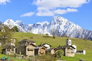 Alpine village and meadows framed by the snowy peak of Pizzo di Prata, Daloo, Chiavenna Valley