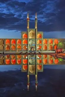 Amir Chaqmaq complex facade illuminated at sunrise and reflecting in a pond, Yazd
