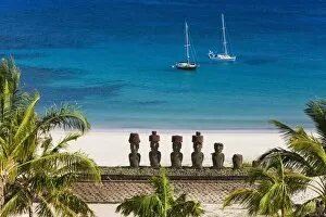 Anakena beach, yachts moored in front of the monolithic giant stone Moai statues of Ahu Nau Nau
