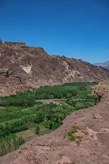 Riverside Prints: Ancient landscape of Shahr-e Zuhak in Bamiyan with river and greenery in Afghanistan under clear blue sky