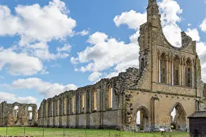 Overgrown Prints: Ancient ruins of a Gothic abbey with arches under a blue sky with clouds at Byland Abbey