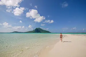 Tahiti Prints: An athletic woman in a bikini walks along the white sandy shoreline of the turquoise