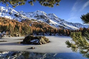 Autumn reflections at Saoseo Lake still partially frozen, Poschiavo Valley, Canton of Graubuenden