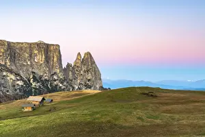 Autumn sunrise over Sciliar peaks and wood huts at Alpe di Siusi (Seiser Alm), Dolomites