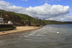 Whitby Prints: Bathers on West Cliff Beach, backed by grassy cliffs in summer, Whitby, North Yorkshire