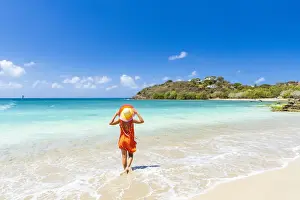 Mid Adults Prints: Beautiful woman with orange dress and straw hat standing on a tropical beach