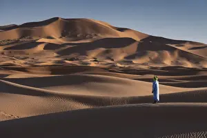Erg Chebbi Prints: A Berber man in traditional dress in the Sand Dunes of Erg Chebbi, Sahara Desert, Morocco