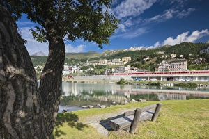 Bernina Express train runs past the village of St. Moritz surrounded by lake, Canton of Graubunden