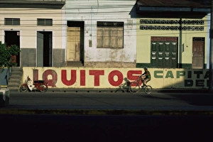 Hispanic Prints: Bicycle cruises past homes