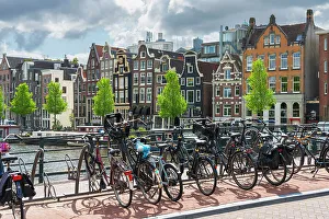Bicycles Prints: Bicycles with houses by Amstel River in the background, Amsterdam, The Netherlands, Europe