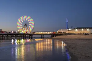 Big wheel and amusements on Central Pier at sunset with Blackpool Tower, Blackpool