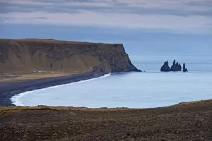 Black sand beach, rock formation and Reynisdrangar sea stacks in the distance