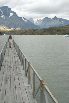 Blonde woman walks to the end of dock on Lago Grey, Torres del Paine, Chile